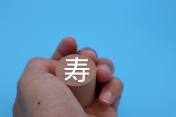 寿と書かれた積み木を持つ人物