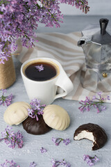 Fototapeta na wymiar Cup of coffee, lilac, marshmallow in dark and white chocolate glaze, coffee maker. Still life
