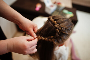 Mother and daughter weekend together at home, mom making hairstyle.