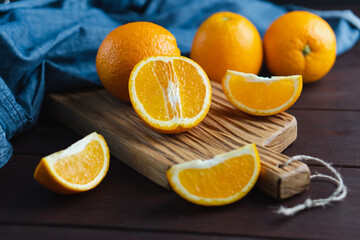 Sliced oranges fruit near denim textile on wooden board. Orange juicy fruit, citrus minimal concept