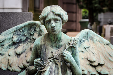 La statua di bronzo ossidato di un angelo sopra una tomba del cimitero monumentale di Milano