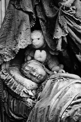 La statua di una bambina che sembra dormire in un piccolo letto a baldacchino su una tomba del...