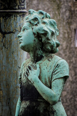 Naklejka premium La statua di bronzo ossidato di una bambina sofferente sopra una tomba del cimitero monumentale di Milano
