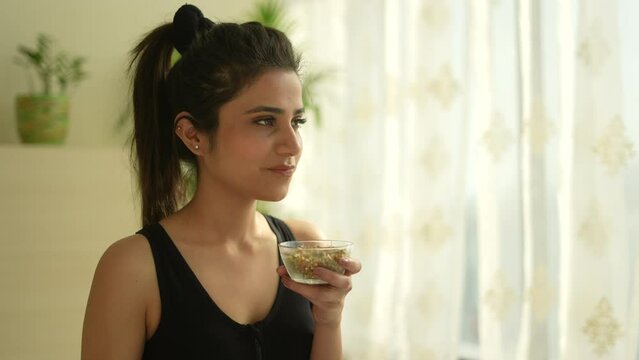 A Young Indian Woman  Eating Sprouts And Healthy Food After Yoga.looking Other Side