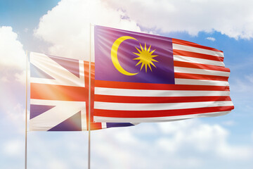 Sunny blue sky and flags of malaysia and great britain