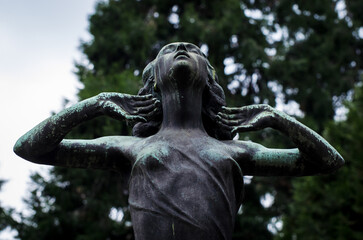 La statua di  bronzo ossidato di una donna sofferente sopra una tomba del cimitero monumentale di...