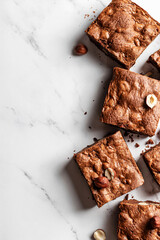 Chocolate brownies with hazelnuts on marble background, flat lay composition, text space on the left