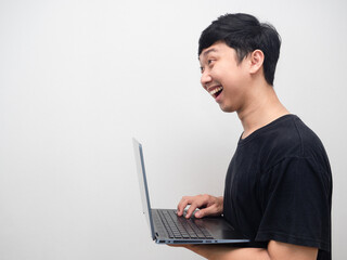 Asian man smiling and using laptop side view