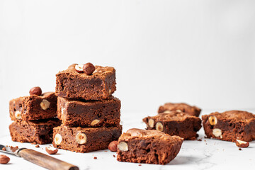 Delicious brownie pieces with hazelnuts in composition on marble background with space for text