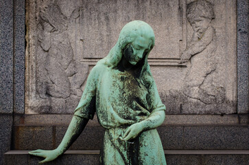 La statua di bronzo di una donna sofferente su una tomba del cimitero monumentale di Milano