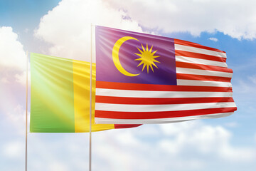 Sunny blue sky and flags of malaysia and mali