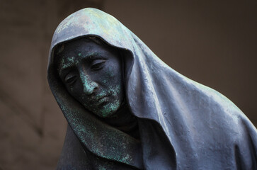 La statua di una donna disperata con la testa coperta da un velo su una tomba del cimitero...
