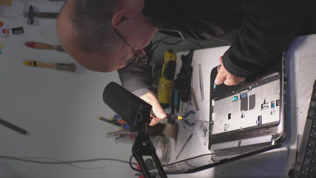 an adult man in a workshop repairs a laptop.vertical video.