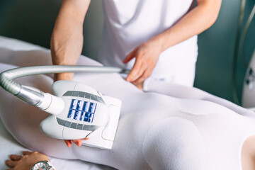 massage in a beauty salon. a client in a special white suit receives an anti-cellulite massage in a beauty salon. The doctor manipulates the device. Body care