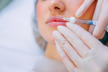 Lip augmentation and correction procedure in a cosmetology salon. The specialist makes an injection in the patient's lips