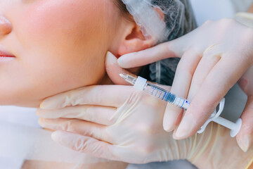 A woman receives a filler injection in her cheeks. Anti-aging care and facelift. cosmetic...