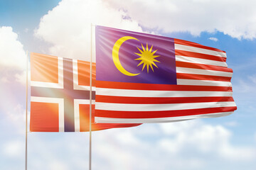 Sunny blue sky and flags of malaysia and norway