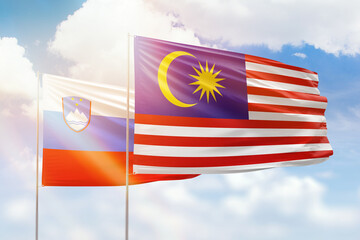 Sunny blue sky and flags of malaysia and slovenia