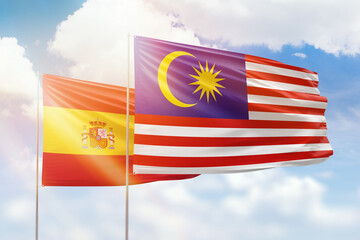 Sunny blue sky and flags of malaysia and spain