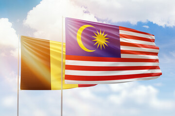 Sunny blue sky and flags of malaysia and belgium