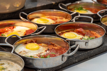 Typical Israeli breakfast buffet at any hotel. Close up of single servings of shakshuka a traditional Israeli egg dish with tomatoes and seasonings.
