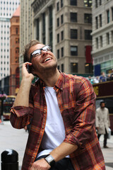Handsome man talking on phone and smiles in New York with joy and happiness