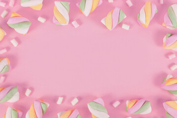 Pastel colored marshmallows forming frame around pink background