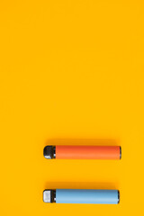 Layout of colorful disposable electronic cigarettes with shadows on a yellow background. The...