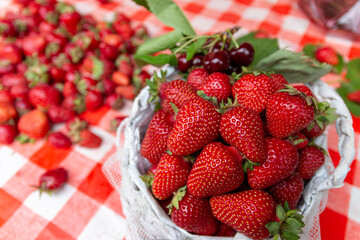 Red ripe fresh strawberry with green leaves in big wooden basket crate on farmers market stall.Close up