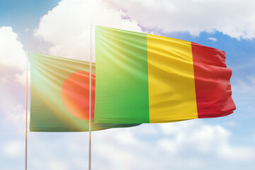 Sunny blue sky and flags of mali and bangladesh