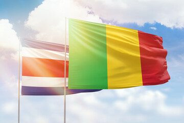 Sunny blue sky and flags of mali and costa rica
