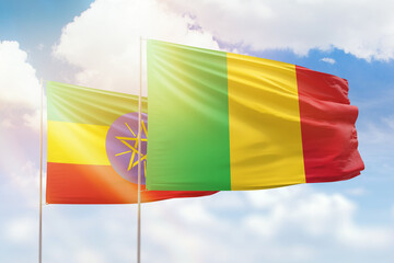 Sunny blue sky and flags of mali and ethiopia