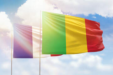 Sunny blue sky and flags of mali and france
