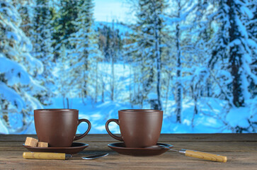 Two cups of tea on background of a winter landscape
