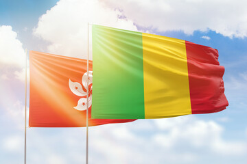 Sunny blue sky and flags of mali and hong kong