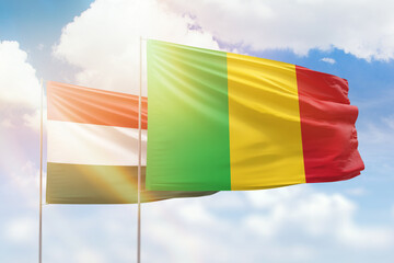 Sunny blue sky and flags of mali and hungary