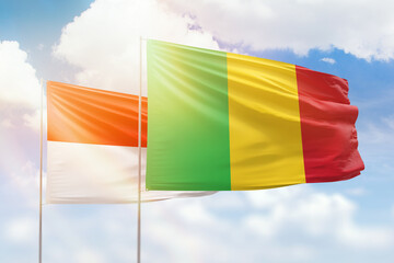 Sunny blue sky and flags of mali and indonesia