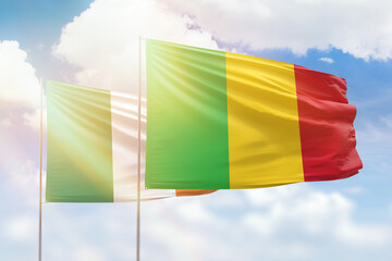 Sunny blue sky and flags of mali and ireland