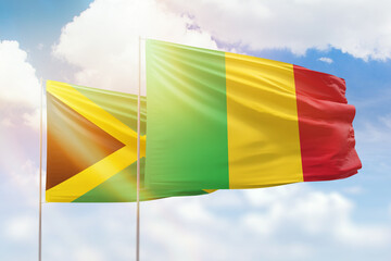 Sunny blue sky and flags of mali and jamaica