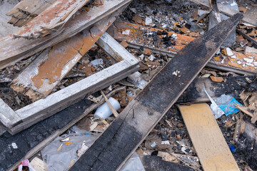 Garbage background from old burnt wooden boards, bricks, plastic. Garbage after the destruction of the house. Waste recycling