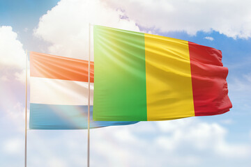 Sunny blue sky and flags of mali and luxembourg