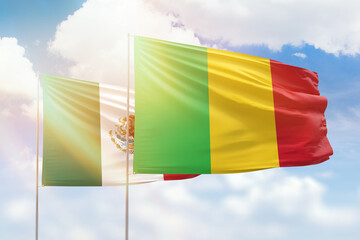 Sunny blue sky and flags of mali and mexico