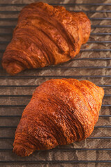 Freshly baked croissants on a cooling rack. Vertical shot, close-up and selective focus on a croissant. Pastry fresh for french breakfast.
