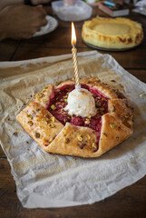 Rustic homemade birthday cake with raspberries, pistachios and puff pastry. Homemade raspberry galette for celebration. Birthday cake with a candle