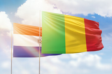 Sunny blue sky and flags of mali and paraguay
