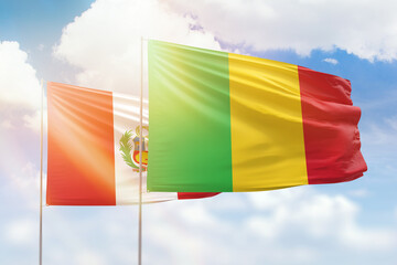 Sunny blue sky and flags of mali and peru