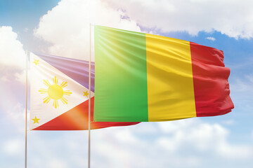 Sunny blue sky and flags of mali and philippines