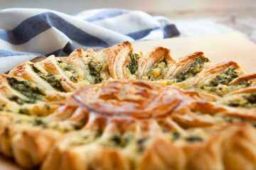 Delicious pie with spinach and ricotta cheese in the shape of a sunflower, towel next to it, close-up.r.