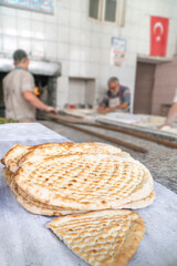 closeup traditional Turkish pita breads over men preparing and baking in a local bakery in Turkey