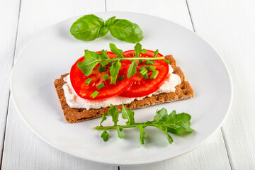 Crispbread with curd cheese, tomatoes, green onions, arugula and basilica. Delicious and healthy breakfast